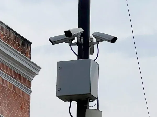 Pair of fixed cameras and equipment cabinet mounted on a pole in an urban area